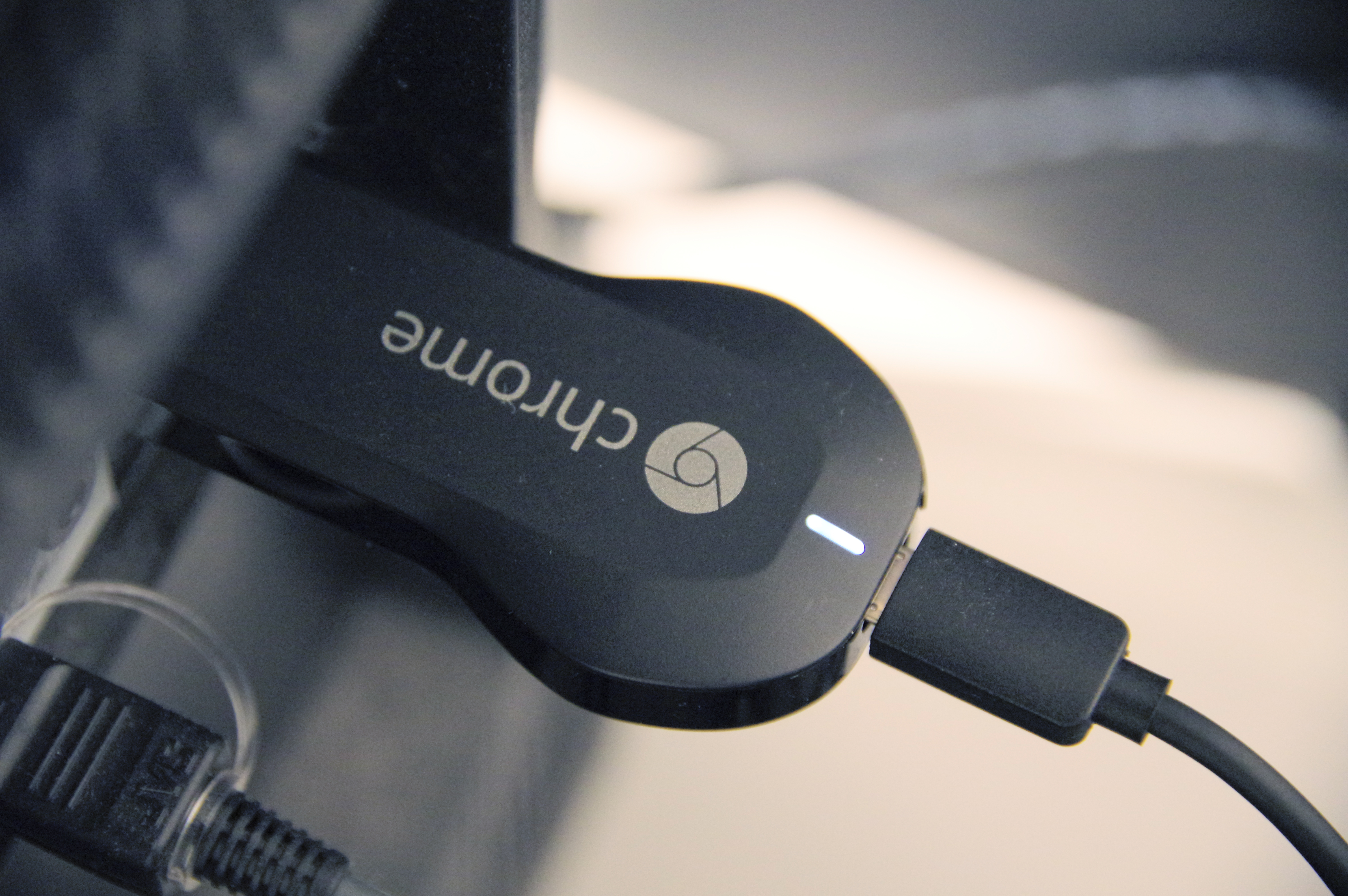 A Chromecast streaming device plugged into a TV HDMI port